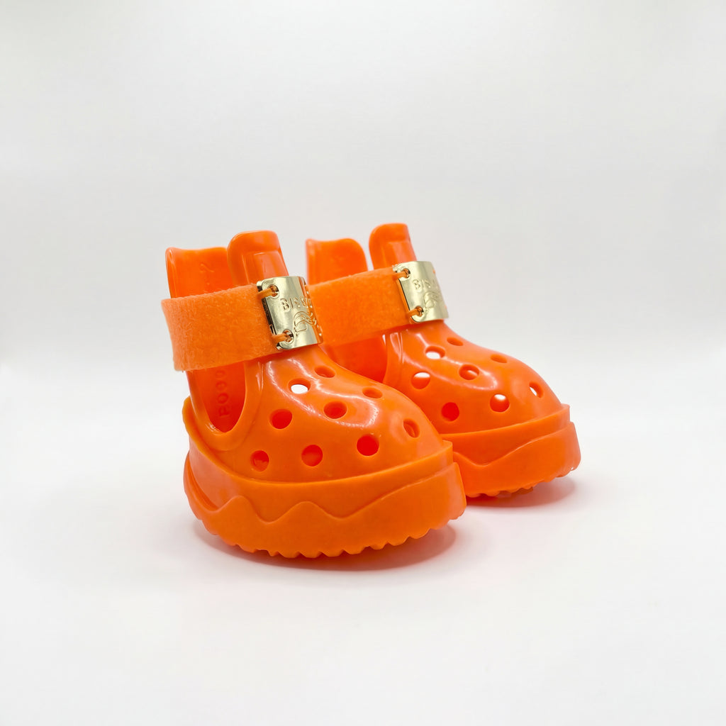 A detailed pair of Blessingmychild V1 high-fashion orange pet footwear featuring authentic front gold emblems on a clean white background