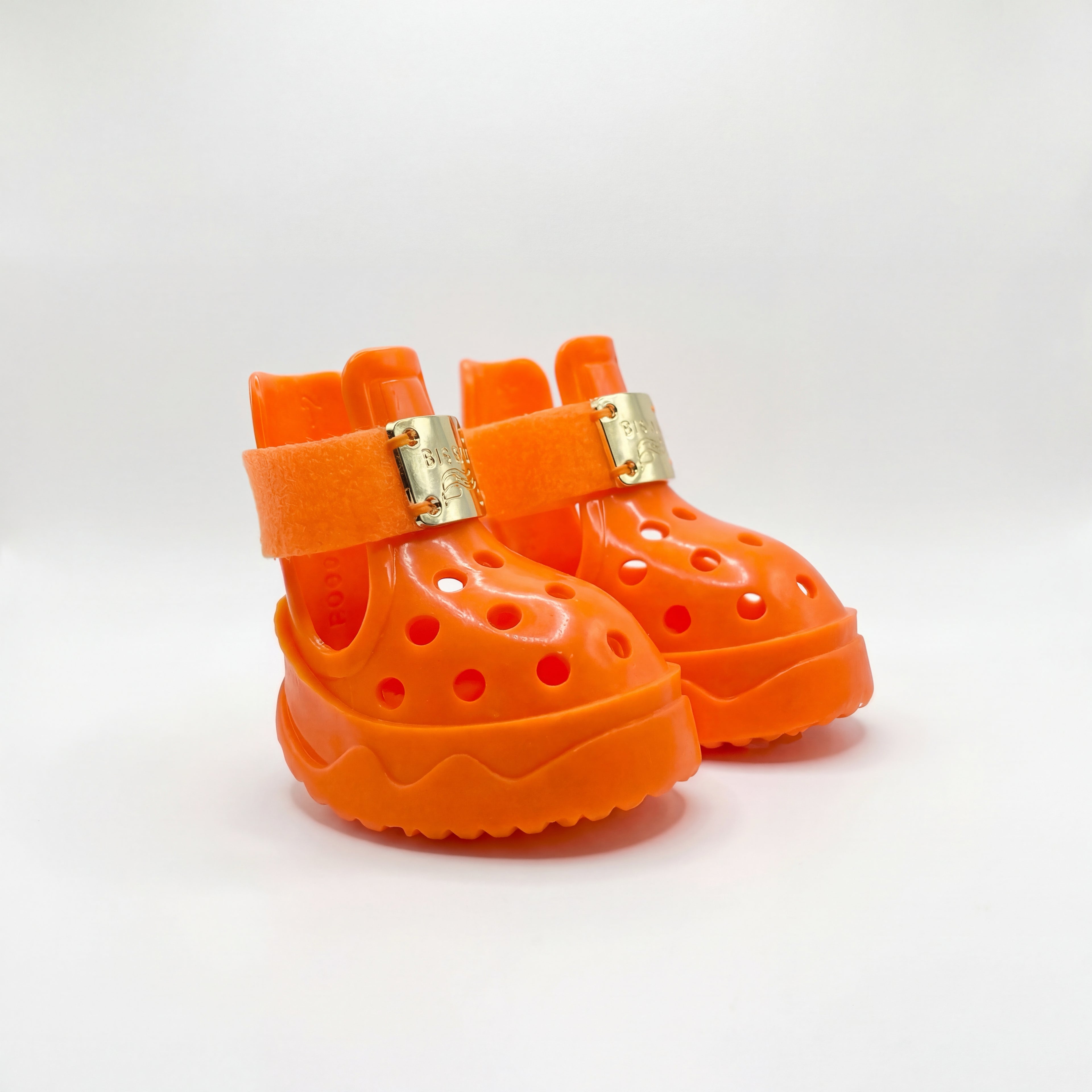 A detailed pair of Blessingmychild V1 high-fashion orange pet footwear featuring authentic front gold emblems on a clean white background