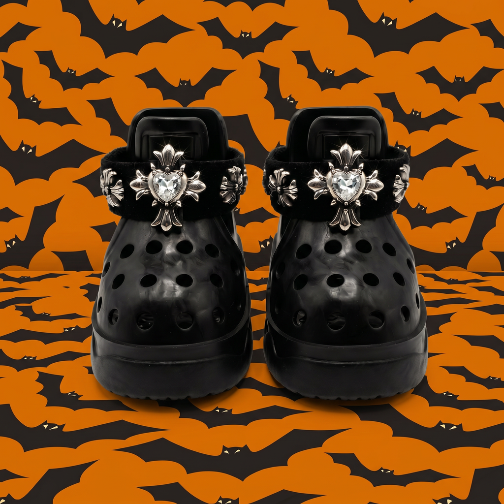 Front view of a pair of BLESSING Halloween limited edition dog sandals in obsidian black, featuring hand-sewn punk silver crosses with heart jewels against an orange bat background.
