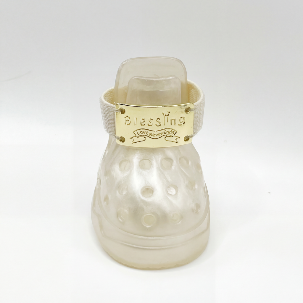 Macro closeup shot of a single Blessingmychild V1 classic pearl white pet sandel with the shiny front-facing brand gold emblem