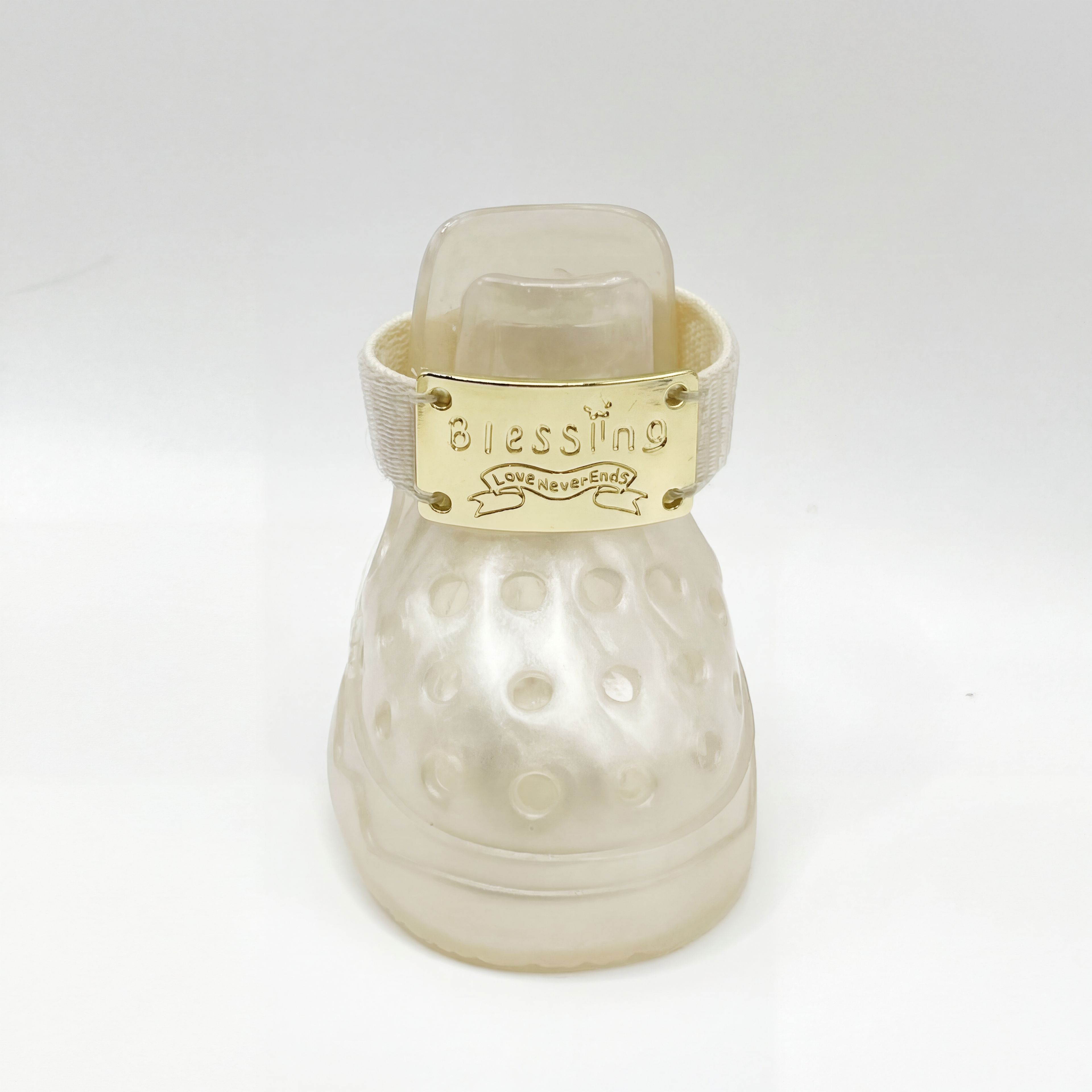 Macro closeup shot of a single Blessingmychild V1 classic pearl white pet sandel with the shiny front-facing brand gold emblem