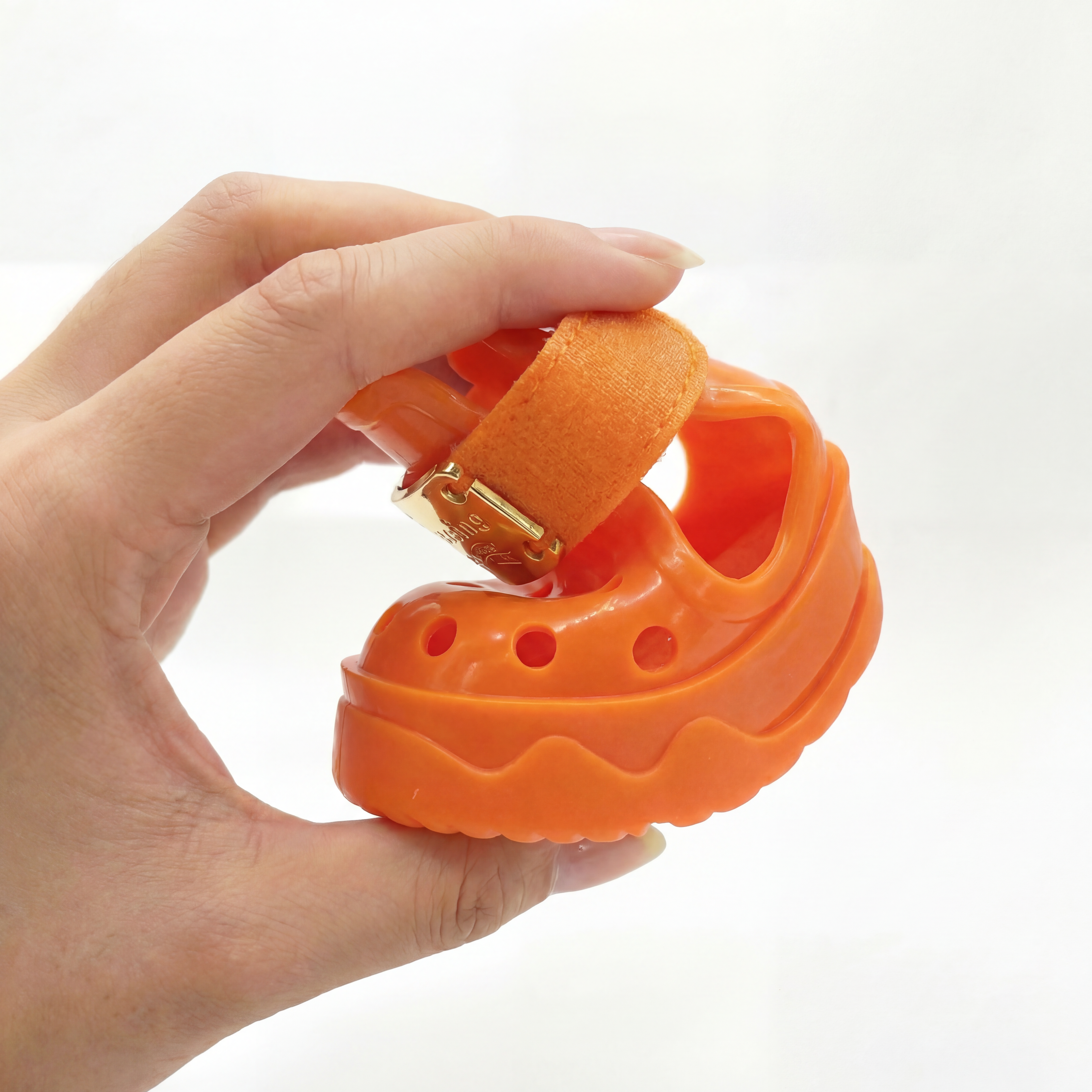 Hand squeezing a Blessingmychild V1 Kelly Orange pet shoe to demonstrate its flexible soft sole and ultra-comfortable material