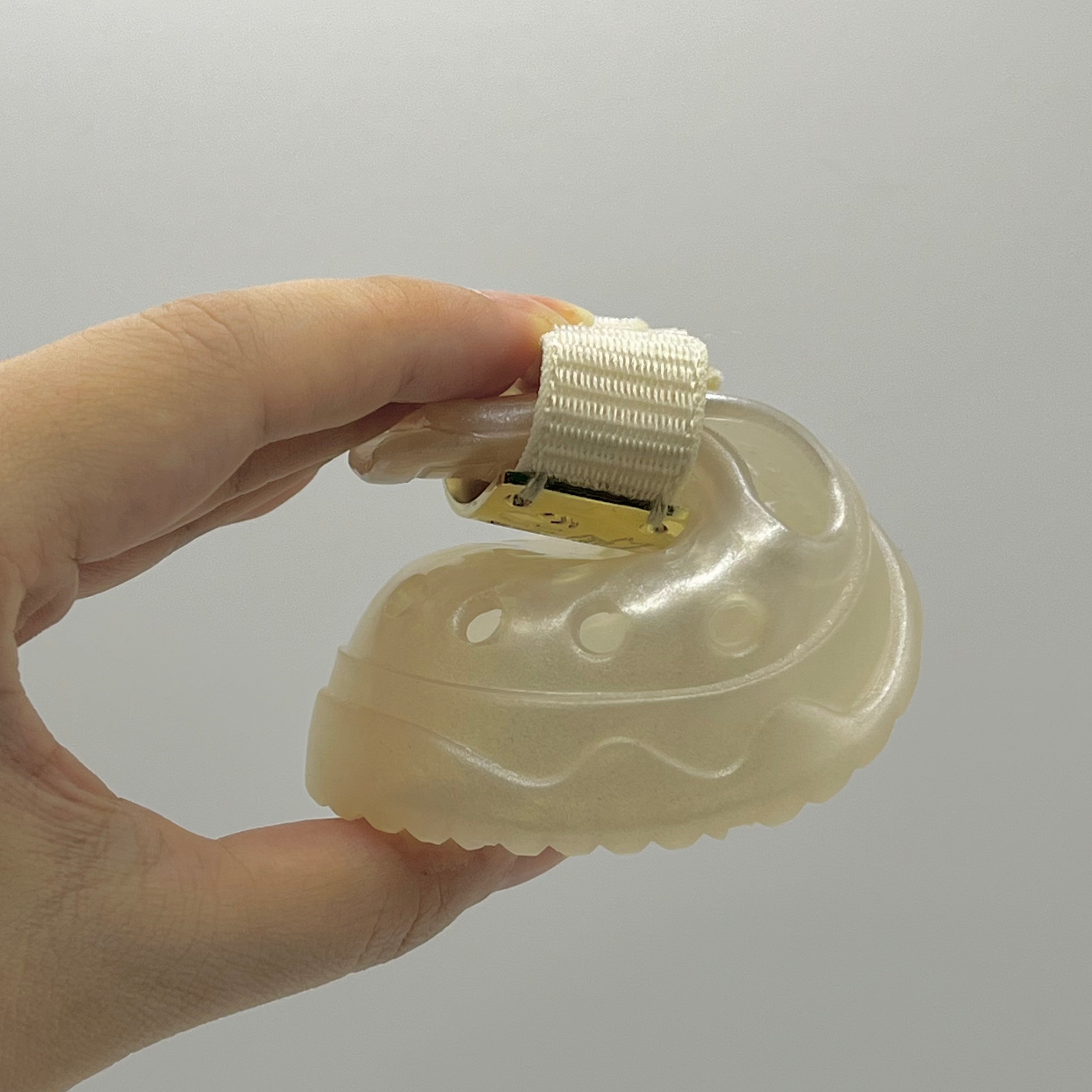 Hand compressing a Blessingmychild V1 classic pearl white pet shoe to demonstrate its high elasticity and flexible soft sole