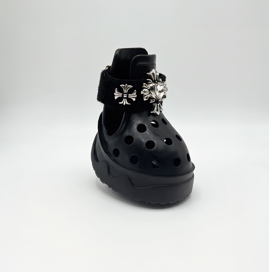 Side view of a single BLESSING black dog shoe, showcasing the detailed hand-sewn silver cross charm on the front strap.